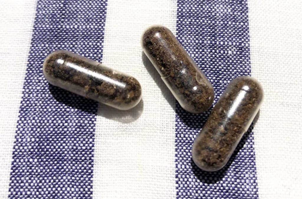Three placenta pills are on top of a navy and white striped linen napkin.