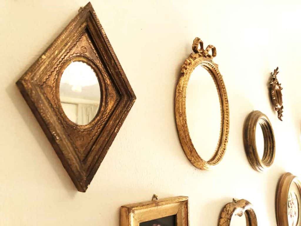 Seven gold frames of different shapes and designs decorate a wall.