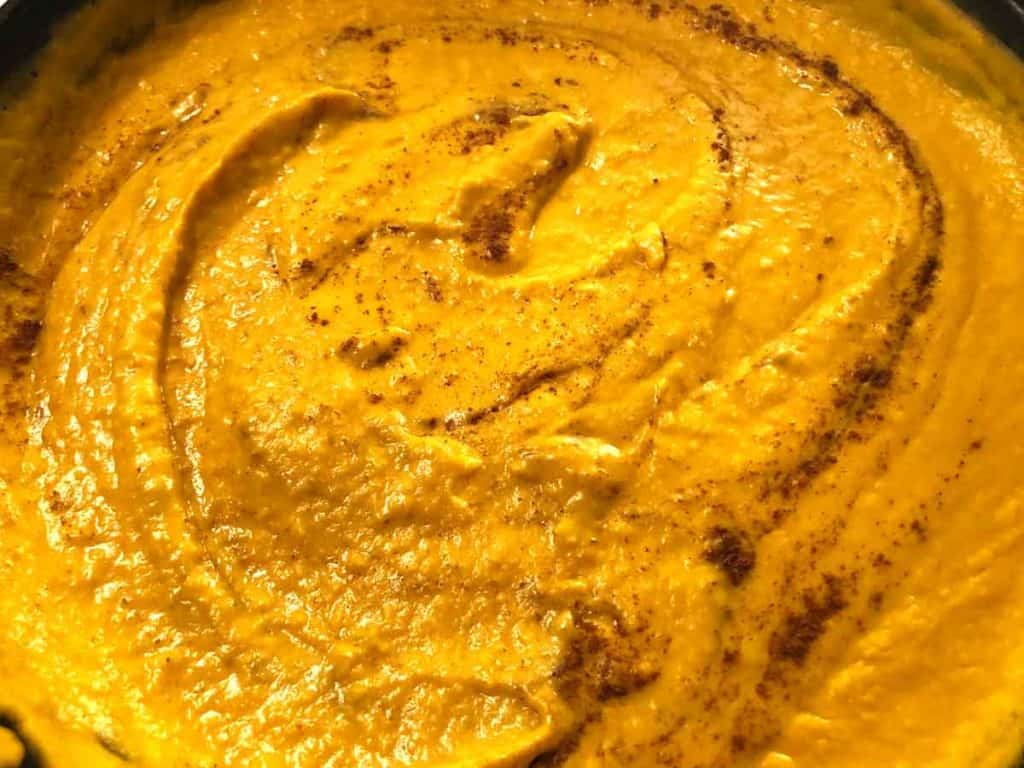 Vegan pumpkin pasta sauce in progress being made. It has been blended and cinnamon is sprinkled on top.