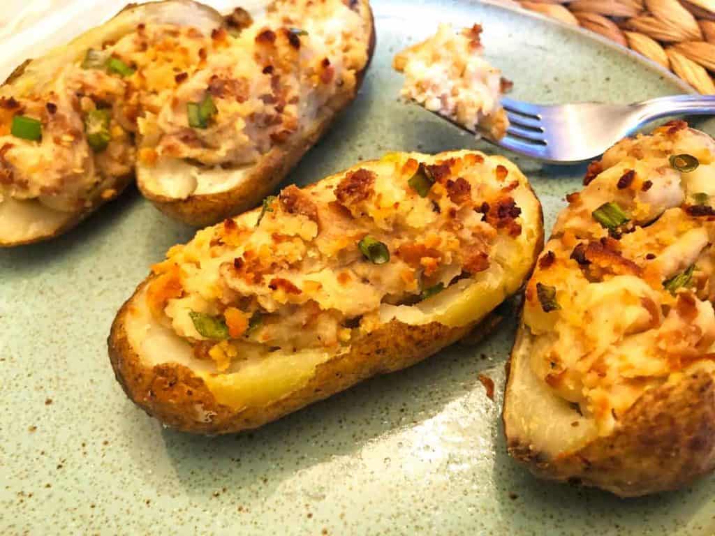 Four plant-based twice baked potatoes are on a light blue plate with a fork.