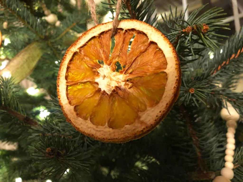 An orange slice Christmas ornament decorates a tree.