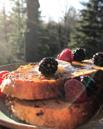 Vegan sourdough french toast topped with berries in the sunlight.