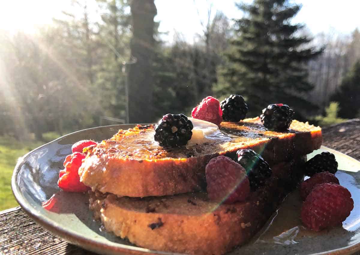 Vegan sourdough french toast topped with berries in the sunlight.