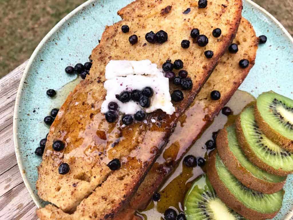 Vegan einkorn French toast is served with dairy-free butter, blueberries, and kiwi.